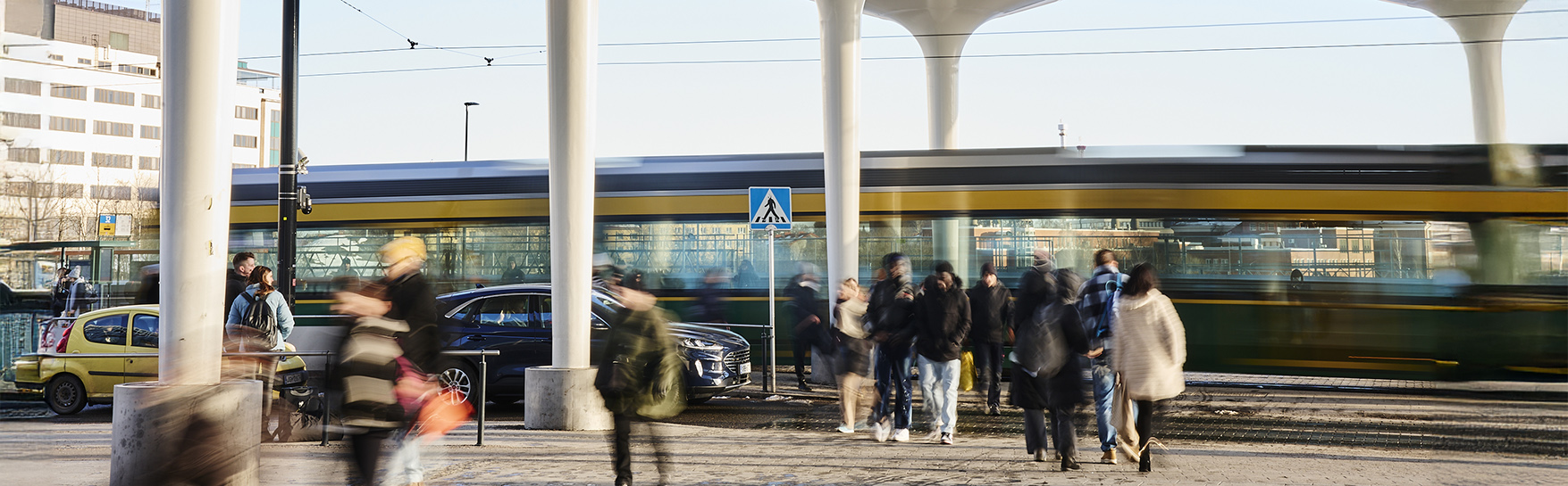 Raitiovaunu kulkee kaupungilla jalankulkijoiden keskellä.